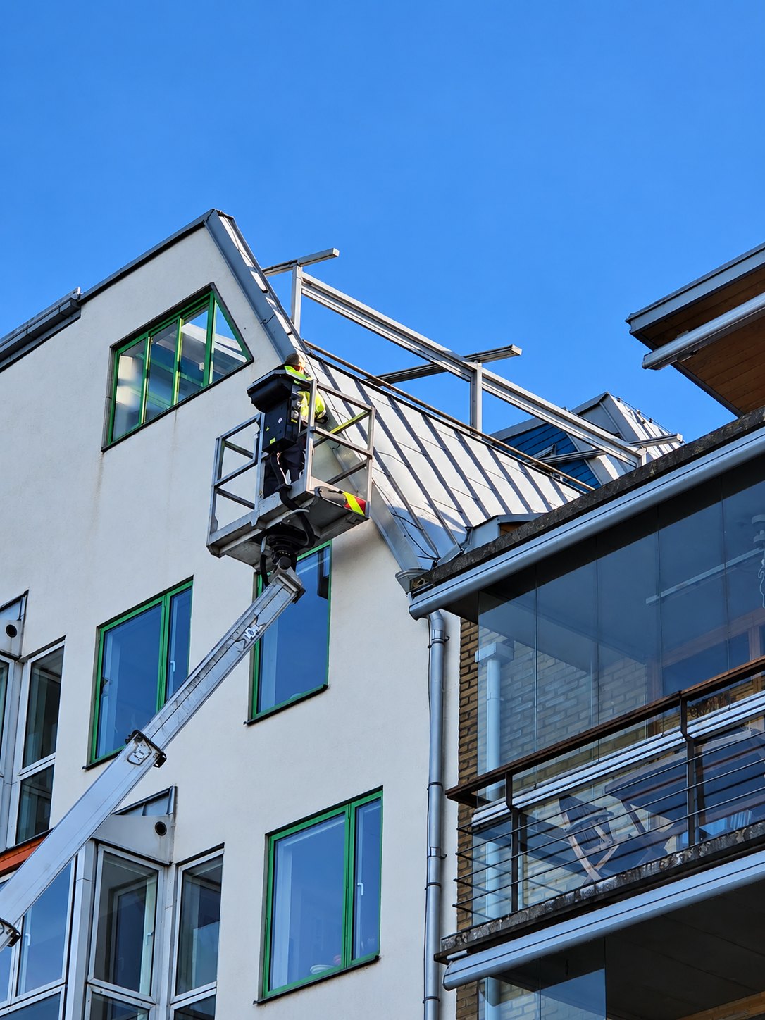 Plåtslagare i skylift vid takplåt på flerbostadshus